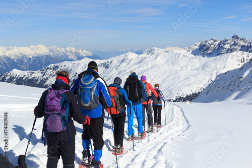 Group of people hiking on snowshoes and mountain snow panorama with blue sky in Stubai Alps, Austria photo