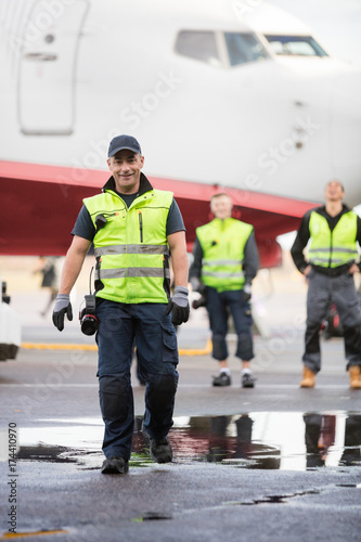 Worker In Walking While Colleagues Standing On Wet Runway