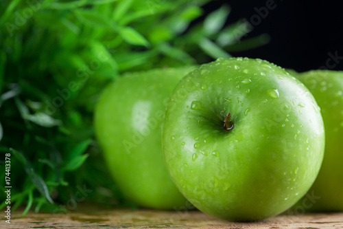 Ripe green apples with water dropletson wooden background photo