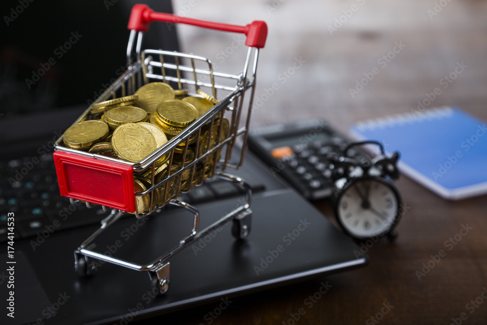 Shopping trolley with coins,  laptop and alarm clock