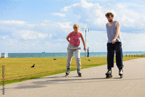 Young pair riding rollerblades in park.