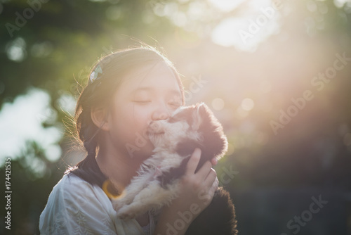 Fotografija Beautiful asian girl playing with siberian husky puppy in the park