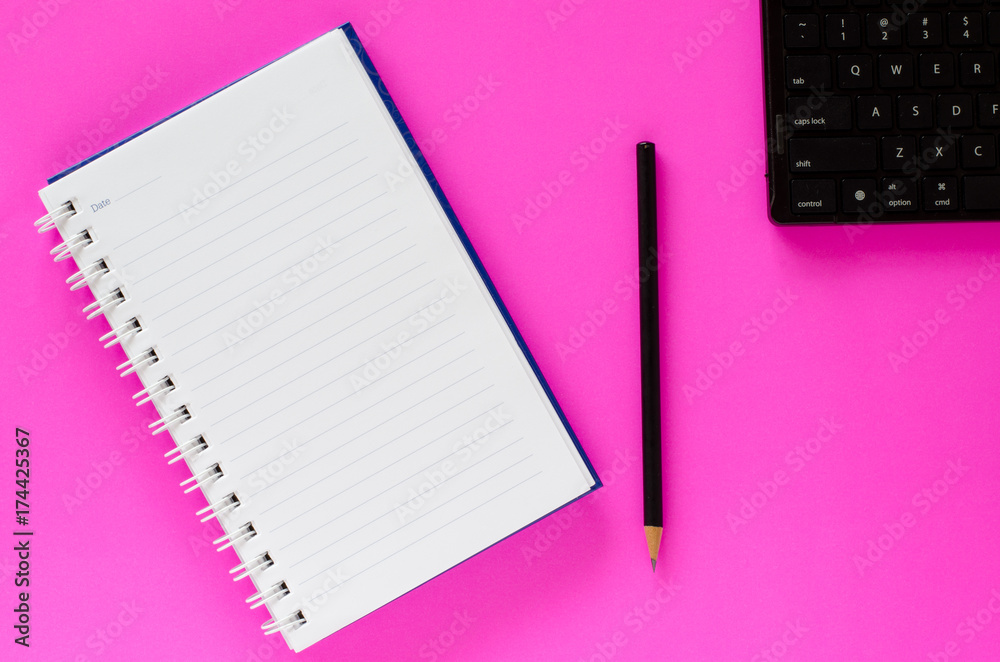 White note book and black pencil and black keyboard on pink color background with copy space. White note book and black pencil and black keyboard on pink color background with copy space.