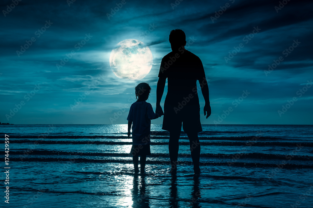 Silhouette of child holding hands her father, standing in the sea.