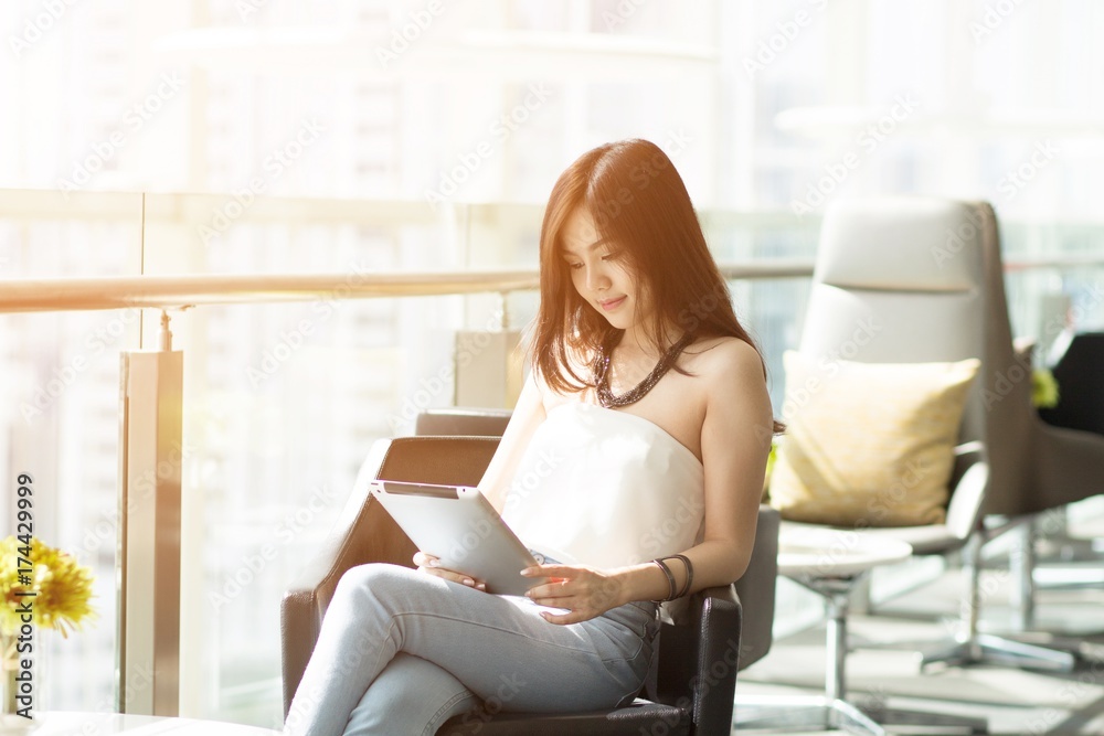 Businesswoman on break. or college student girl using her tablet computer Sit on a lifestyle chair. / concept product presenter. Businesswoman on break. or college student girl using her tablet computer Sit on a lifestyle chair. / concept product presenter.