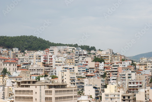 View of an agglomerated cityscape with modern style residelntial aartment buldings. Neutral pastel color cityscape with a patch of forest in the background.
