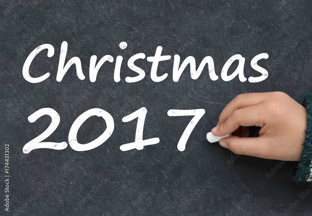 Fototapeta premium Little boy writing Christmas 2017 on a blackboard