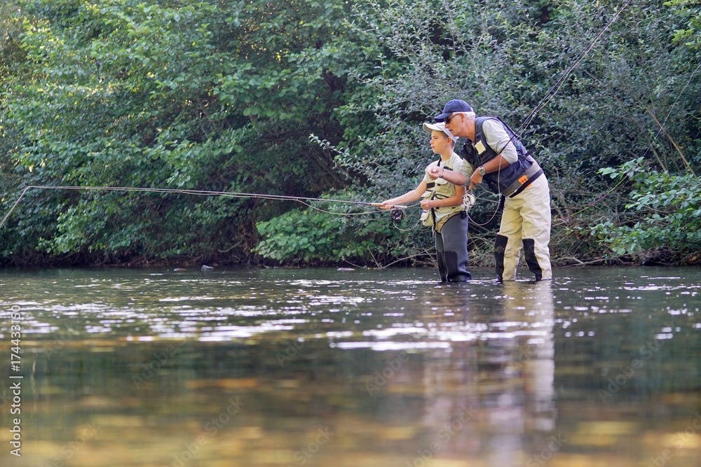 Father teaching son how to fly-fish in river Father teaching son how to fly-fish in river