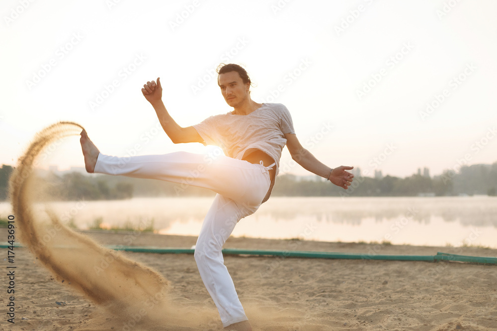 Athletic capoeira performer workout training on the beach sunris Athletic capoeira performer workout training on the beach sunris