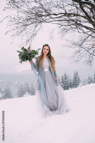 Beautiful winter portrait of young woman in the winter snowy scenery.