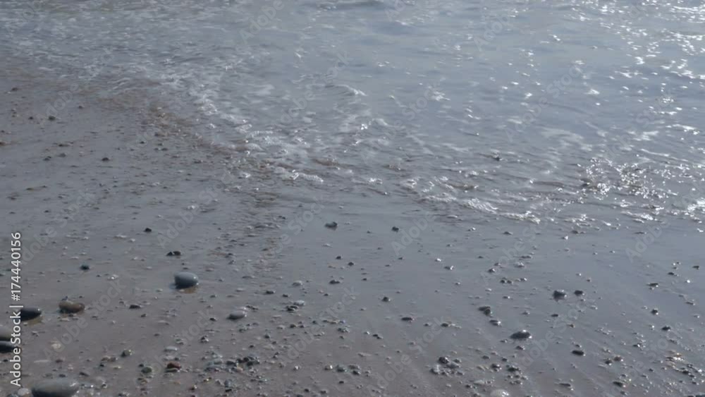 Wave with white foam. Beach with sand and pebbles. Wave with white foam. Beach with sand and pebbles.