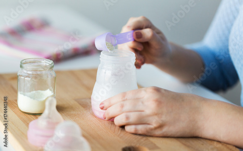 hands with bottle and scoop making formula milk