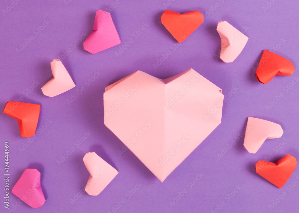 Small and Large Red, Bright and Pale Pink Paper Origami Hearts on Purple Background