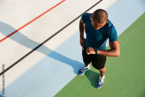 Fototapeta Naklejka Na Ścianę i Meble -  Top view of a african sportsman looking at his wristwatch