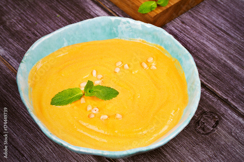 Creamy pumpkin (or butternut squash) soup in a bowl on wooden background, horizontal