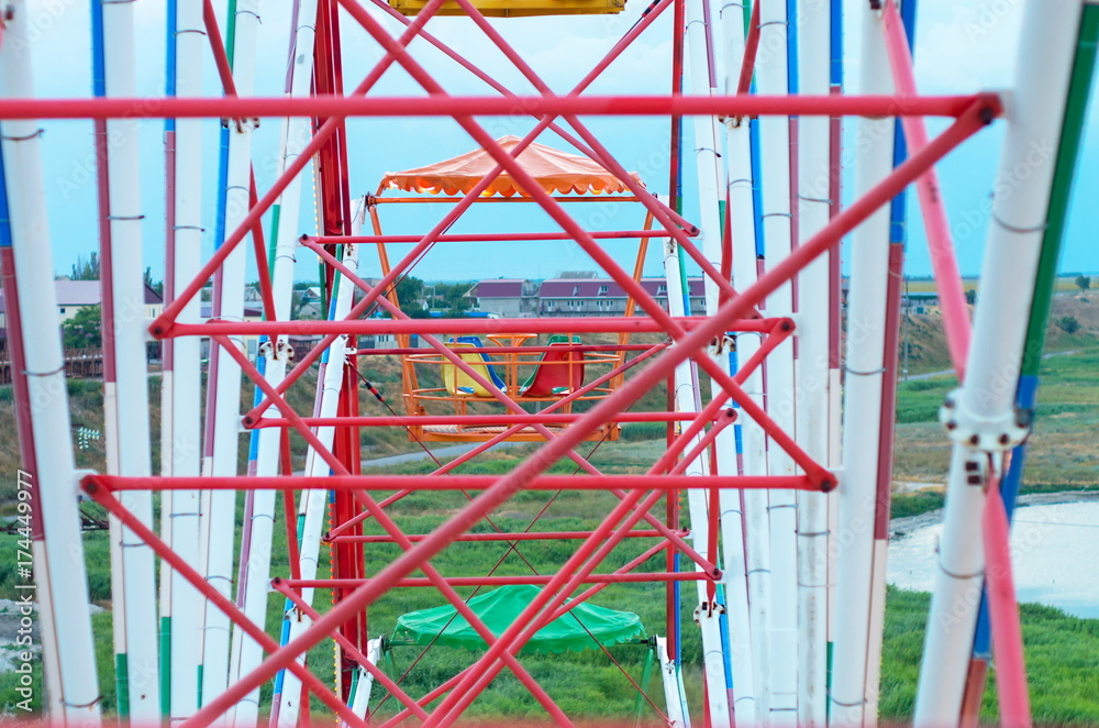 design of a ferris wheel. Multicolored booths with chairs at a height.