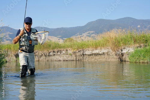 Fly-fisherman catching brown trout in North American river