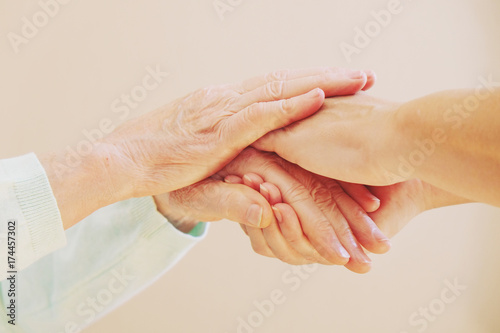 Close up of senior woman and young woman holding hands. Care and support concept 