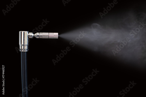 Nozzle sprays liquid into vapor black background photo