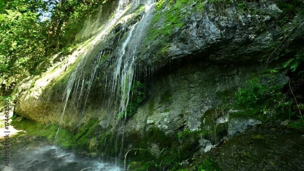 Waterfall in the autumn forest. Yellow foliage in the foreground.