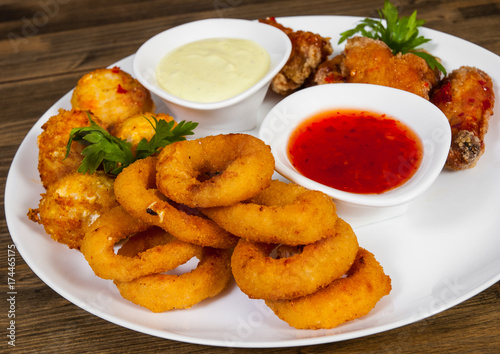 set of appetizers. salted balls, chicken wings, onion rings, sauce on a wooden background. 