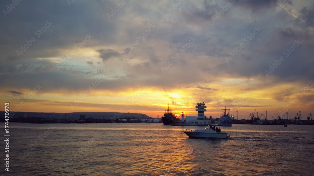 Sunset at the sea port Varna and sailing motor boat
