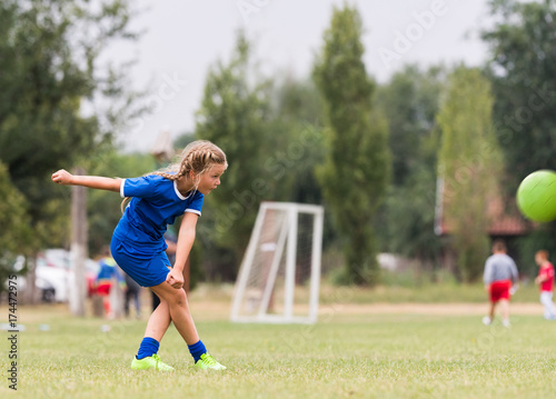 Kids soccer football - little girl is shooting ball at soccer field