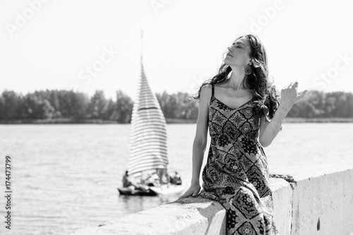 Middle aged stylish woman wear in long silk dress on a beach rest at good sunny day, nature background 