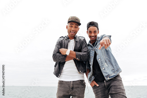 Two young african men friends walking outdoors listening music. © Drobot Dean