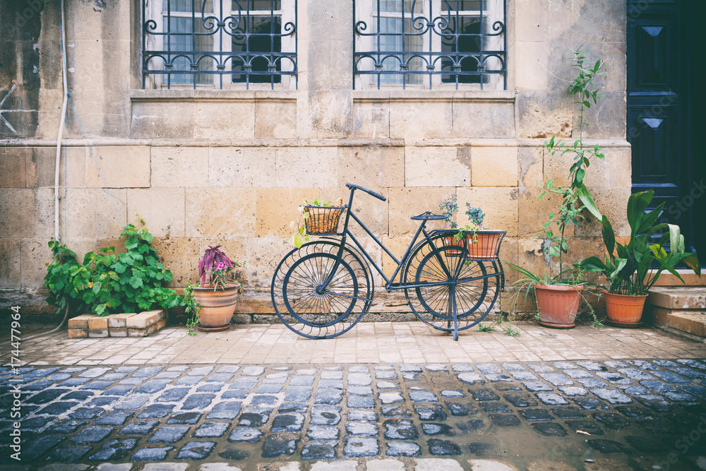 Bicycles parked near stone brick wall of old house among plants in pots in Icheri Sheher, Baku, Azerbaijan