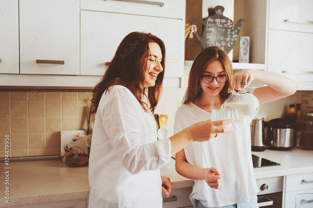 mother having breakfast with teen daughter at home in modern white kitchen. Casual lifestyle in real life interior mother having breakfast with teen daughter at home in modern white kitchen. Casual lifestyle in real life interior