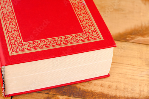 Closed red book on wooden background