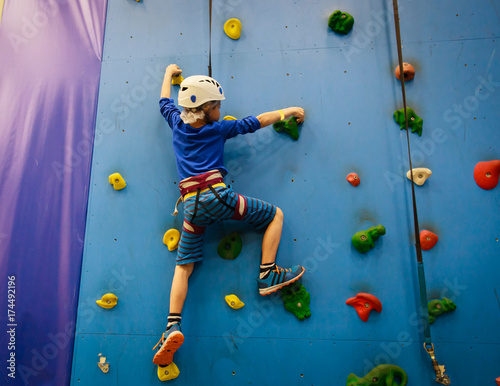 little boy climbing wall in sport center