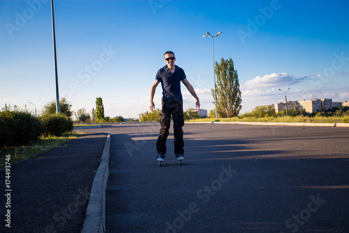 Happy young man rollerblading in city park at sunset. Outdoor, recreation, lifestyle, rollerblading © Svetlana