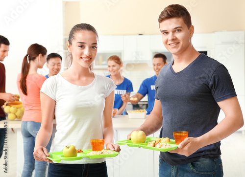 Happy teens holding trays w...