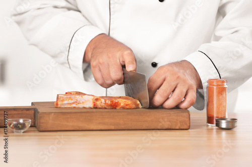 Male chef cutting meat in kitchen, closeup