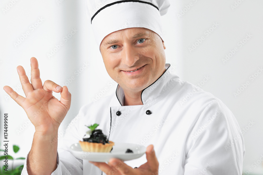 Male chef holding plate with dessert in kitchen Male chef holding plate with dessert in kitchen