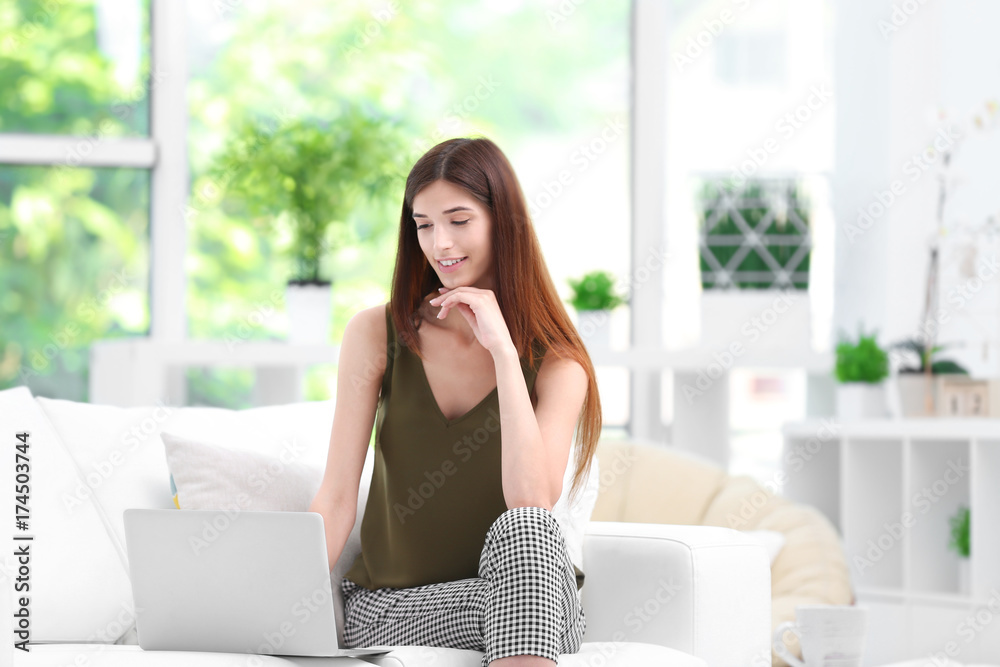 Young woman with laptop in living room Young woman with laptop in living room