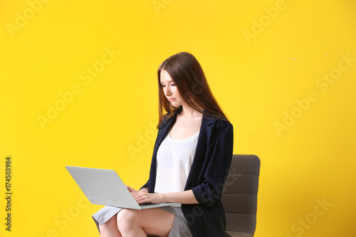 Young woman with laptop on color background