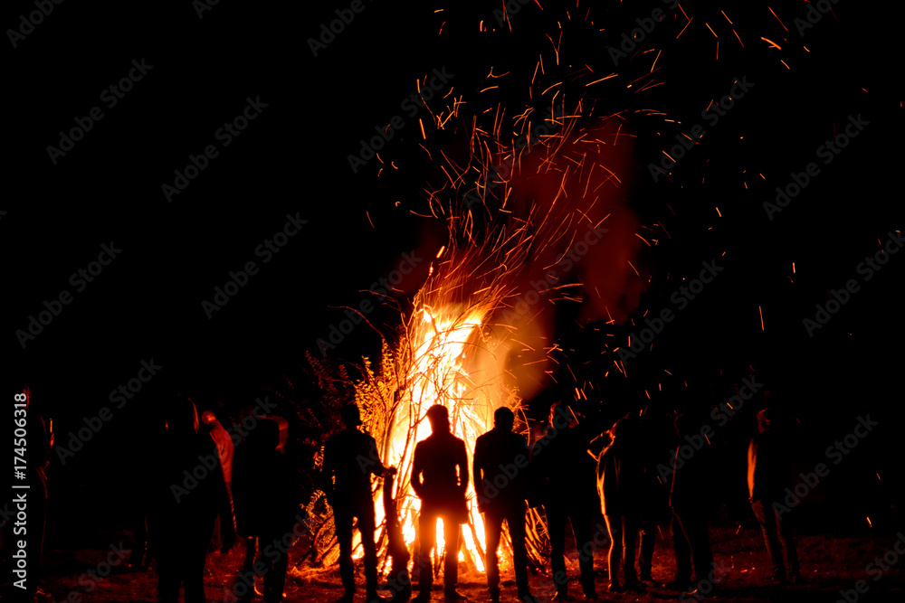 People stand near a big fire at night - obrazy, fototapety, plakaty 