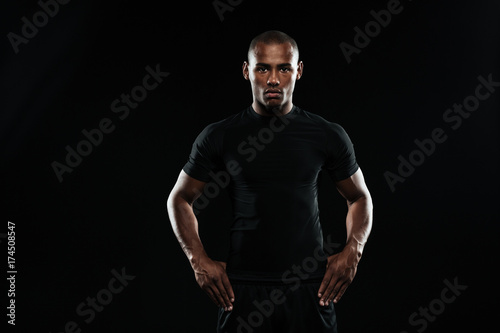 Serious afro american sports man with arms  on his hips looking at camera