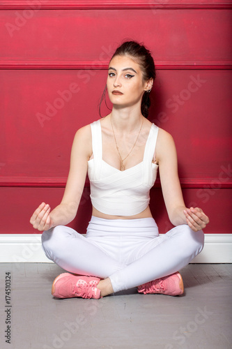 Girl in a yellow swimsuit in the gym teaches yoga with dumbbells