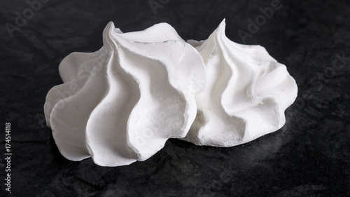 Photos Sweet white meringue is isolated on a dark background.