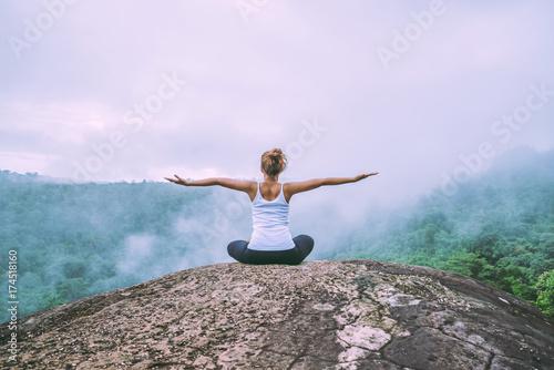 Asian women relax in the holiday. Play if yoga. On the Moutain rock cliff