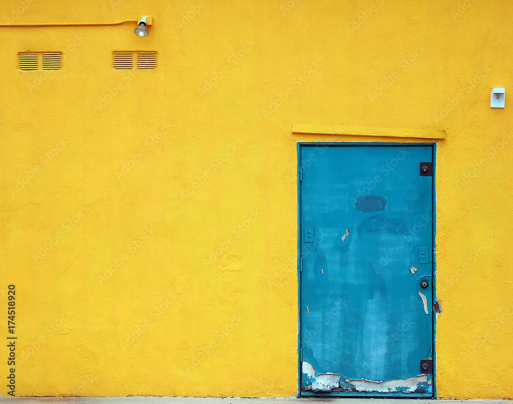 Aqua blue industrial door on a bright yellow building Aqua blue industrial door on a bright yellow building