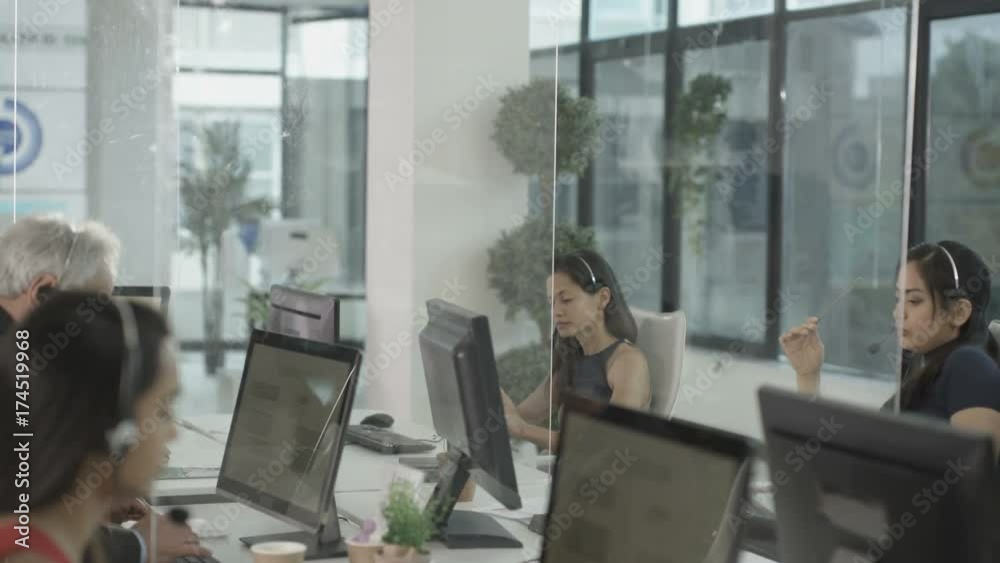 Business manager talking to his employees in busy modern call centre Business manager talking to his employees in busy modern call centre