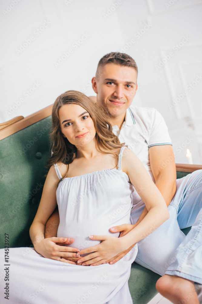 pregnant woman and husband are happy couple expecting a baby on sofa. pregnant woman and husband are happy couple expecting a baby on sofa.