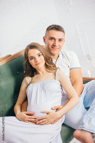 pregnant woman and husband are happy couple expecting a baby on sofa. photo