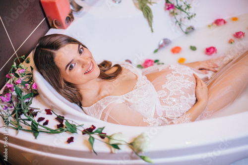 Obraz na płótnie beautiful pregnant woman in a bathroom with milk and flowers. w salonie