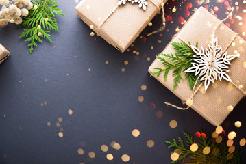 Christmas handmade gift boxes craft paper decorated on dark background top view. Merry christmas greeting card, frame. Winter xmas holiday theme. Happy New Year. Flat lay. Twinkle glitter bokeh light